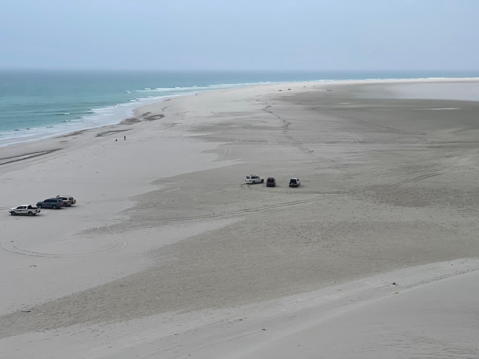 Five four-wheel-drive vehicles parked together on open sand