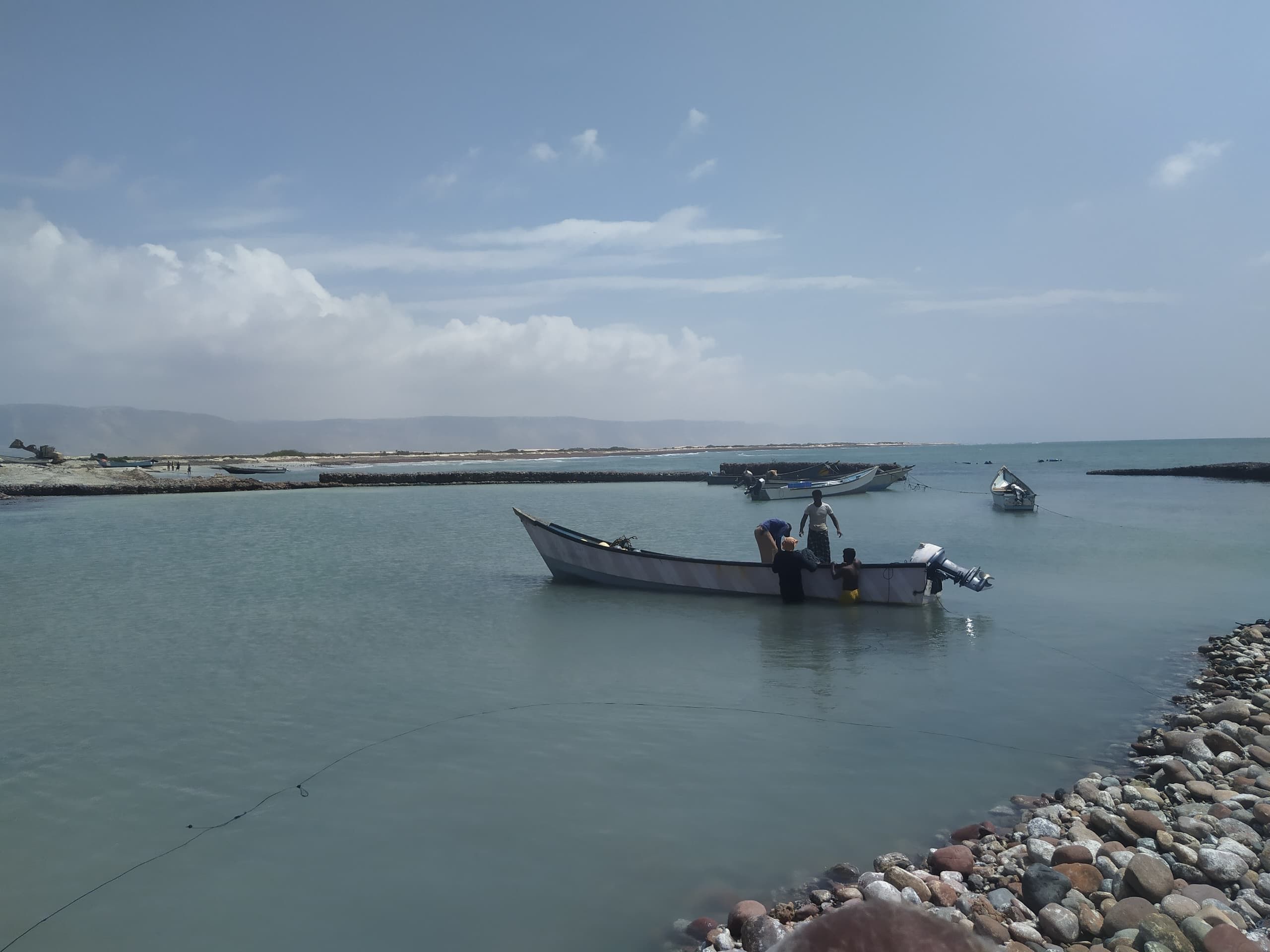 Fishing boats moored in shallow water, one man standing aboard