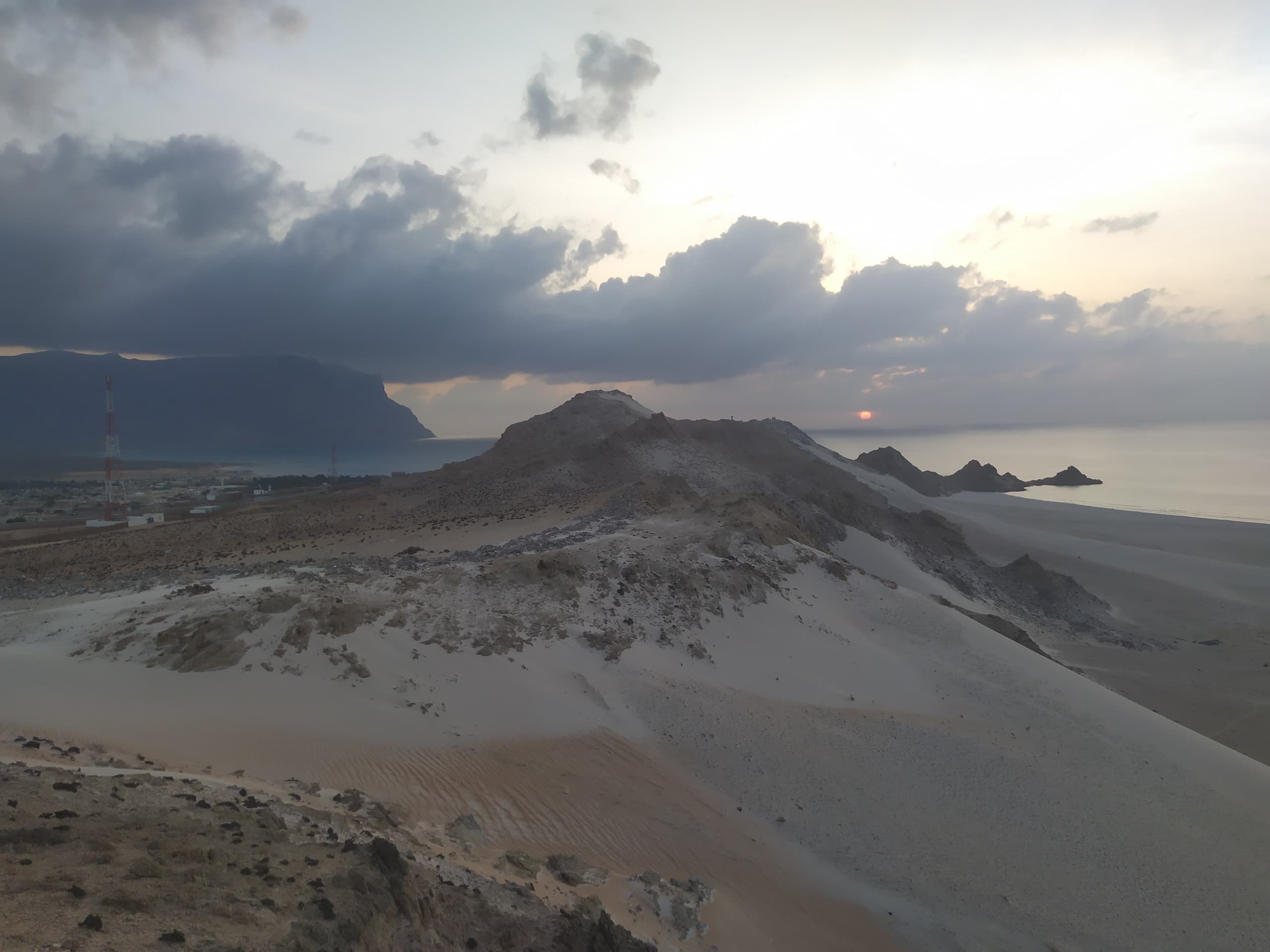Pale dunes running out towards the sea under a heavy bank of storm cloud